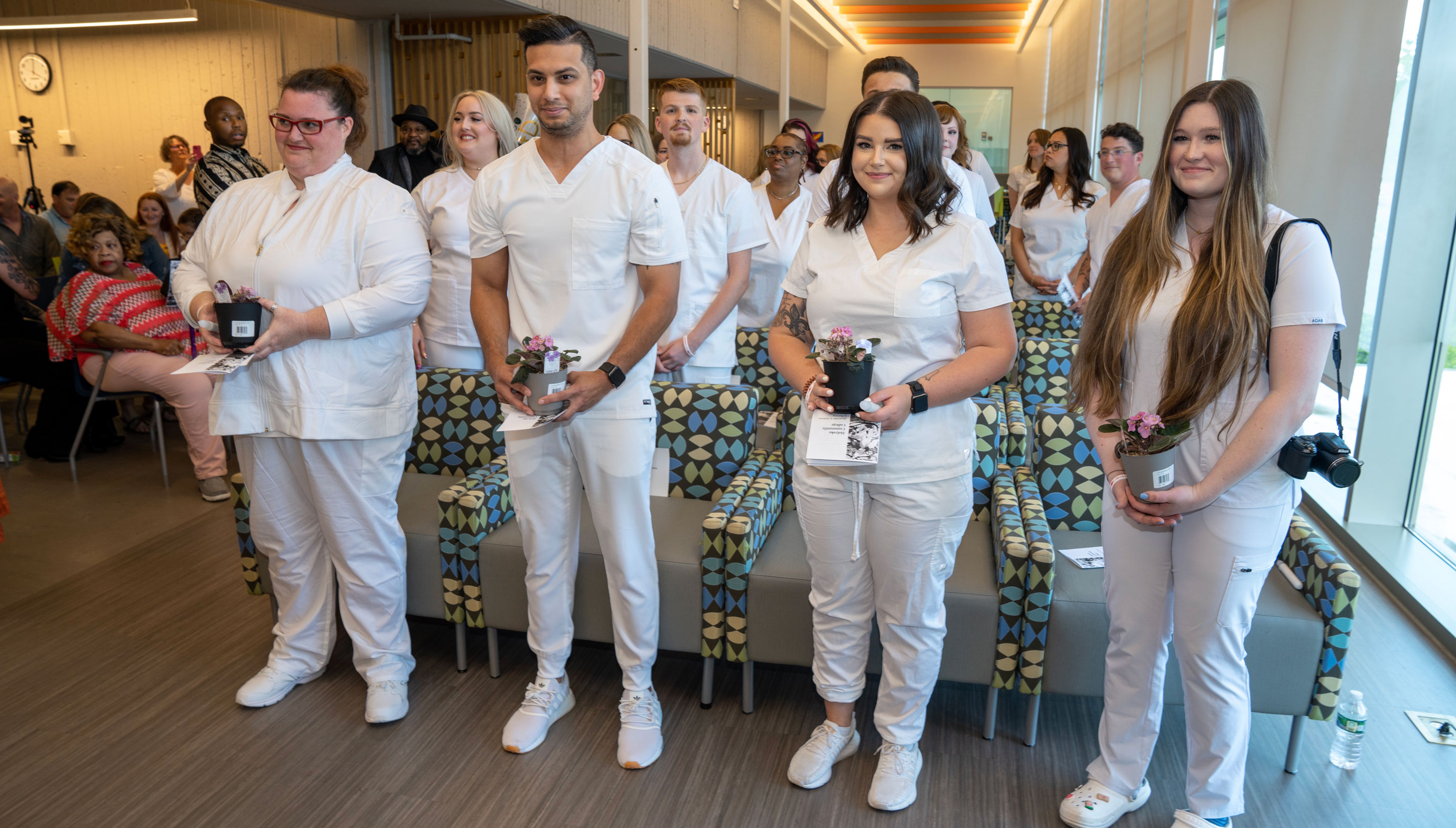 A group of nursing graduates wearing white scrubs